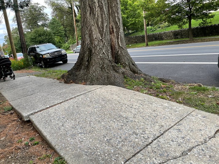 broken sidewalk next to brand new road.